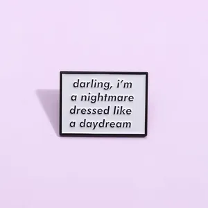 Macro shot of rectangular enamel brooch with art text on a soft purple background