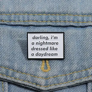 Close-up of minimalist enamel badge with quote pinned on a blue denim jacket pocket