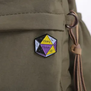 Detailed close-up of a D20 non-binary pride enamel pin with they/them pronouns on a bag