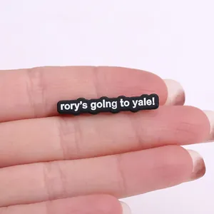 Close-up van zwarte emaille speld met de tekst Rory's Going to Yale erop