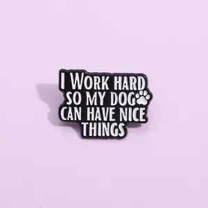 Détail du pin's en émail noir avec empreinte de patte et texte I work hard so my dog can have nice things