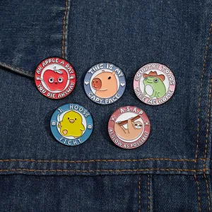 Detail of five cute cartoon enamel pins with animals and fruit on blue denim fabric