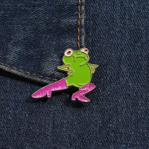 Détail macro d'un pin's grenouille rigolo avec bottes roses pailletées sur denim