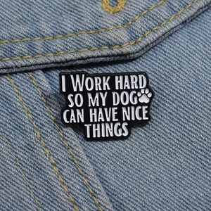 Détail d'un pin's émaillé noir sur veste en jean avec patte de chien et citation