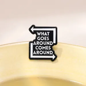 Detail of enamel pin with What Goes Around Comes Around text and arrow design