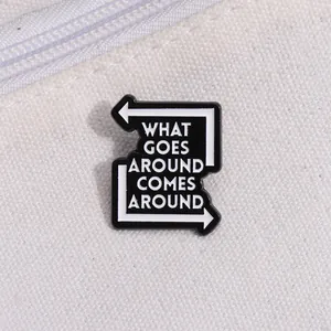 Premium black and white enamel pin with 'What Goes Around Comes Around' text on canvas