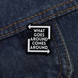 Close-up of What Goes Around Comes Around enamel pin on blue denim fabric background