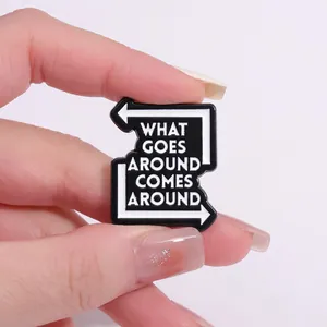 Detail of enamel pin with 'What Goes Around Comes Around' text and arrow design