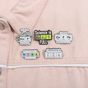 Set of 5 science enamel pins featuring chemical element wordplay on pink denim jacket