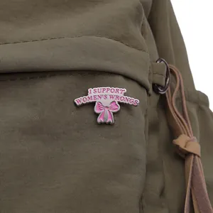 Gros plan détaillé du pin's nœud rose avec slogan sur texture de tissu olive foncé