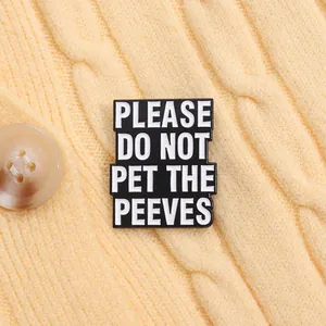 Close-up of black enamel pin with Please Do Not Pet The Peeves text on a cable knit sweater