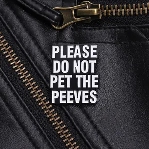 Detail of funny enamel pin with PLEASE DO NOT PET THE PEEVES text on leather jacket