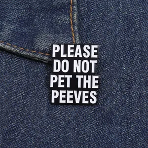 Macro shot of rectangular enamel pin with text Please Do Not Pet The Peeves on denim