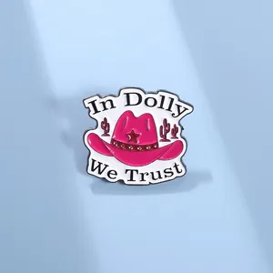 Detail of pink cowboy hat enamel pin with In Dolly We Trust slogan and cactus