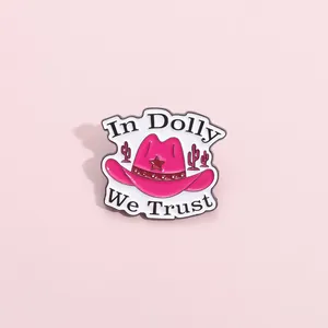 Detail of pink enamel cowboy hat pin featuring stars, cacti, and In Dolly We Trust text