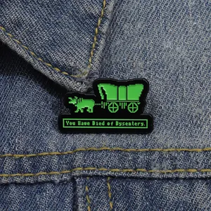 Detail of pixel art enamel brooch on denim jacket with retro video game text