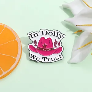 Detail of pink cowboy hat enamel brooch featuring In Dolly We Trust text and star