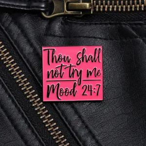 Pink square enamel brooch with Thou shall not try me 24:7 text on a leather jacket