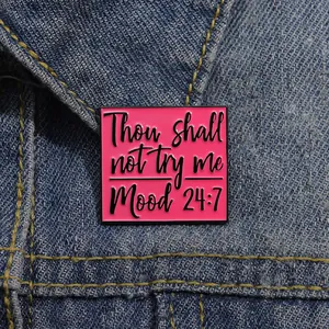 Close-up of pink enamel mood 24:7 brooch pinned on blue denim fabric texture