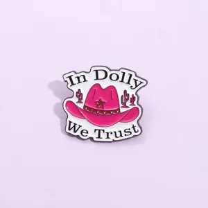 Pink enamel cowboy hat brooch featuring Dolly text and cactus design on purple background