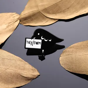 Black bird enamel pin with They/Them pronouns on a reflective background