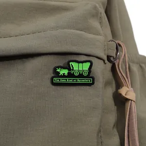 Close-up of retro pixel art enamel pin with wagon design on green canvas backpack