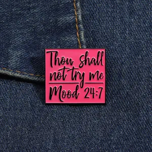 Detail showing pink metal brooch with Thou shall not try me text on denim fabric