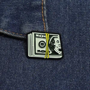 Détail d'un pin's émaillé billet de 100 dollars sur un tissu en jean bleu