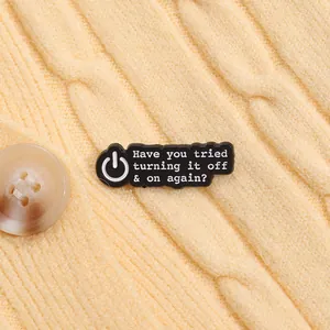 Détail du pin's émaillé avec citation humoristique sur un pull en maille jaune
