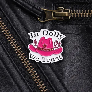 Close-up of pink enamel cowboy hat pin with In Dolly We Trust text on black leather jacket