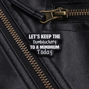 Détail d'un pin's en émail avec slogan humoristique sur une veste en cuir noir punk