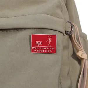 Detail of red enamel badge with funny stickman and Bad text on a canvas bag
