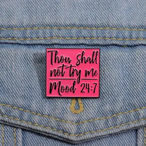 Detailed view of pink enamel mood 24/7 pin badge on blue denim fabric background