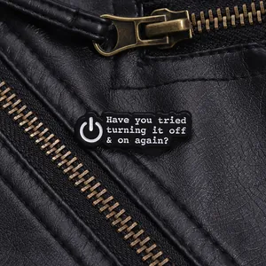 Gros plan d'un pin's en émail noir avec citation informatique sur une veste en cuir