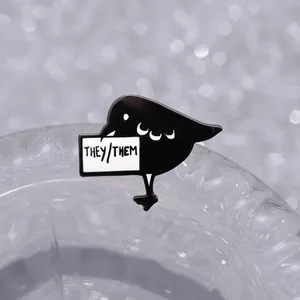 Black bird enamel pin badge with They/Them pronoun sign on a clear glass rim