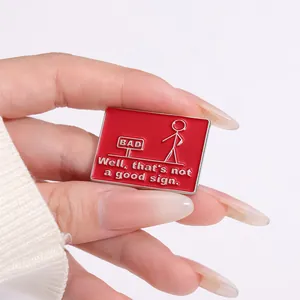 Close-up of red enamel stickman brooch pin held by hand to show compact size