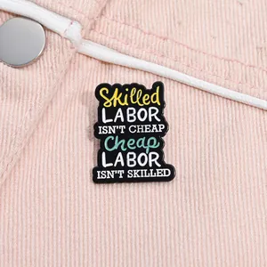 Détail d'une broche en émail avec citation sur un fond en denim rose vif