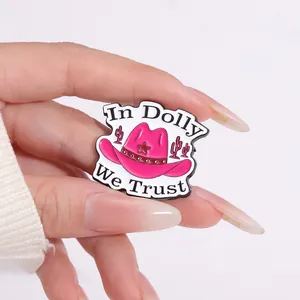 Detailed close-up of pink cowboy hat enamel pin with In Dolly We Trust lettering