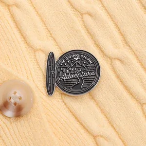 Détail d'un pin's aventure sur un pull avec des motifs de montagnes et de forêts sauvages