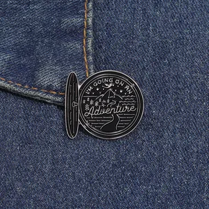 Détail du pin's aventure sur denim montrant les montagnes, la tente et le motif dragon
