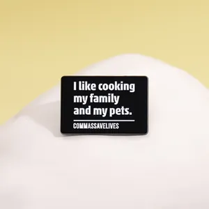 Vue rapprochée d'une broche rectangulaire en émail noir avec typographie blanche