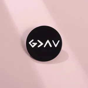 Detailed view of round black enamel brooch featuring white G > ∧ V geometric symbols