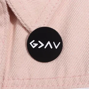 Cool black enamel round badge with white geometric symbols on pink fabric background