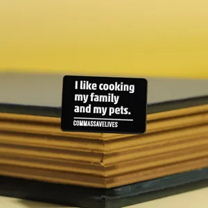 Détail d'un badge rectangulaire en émail noir avec texte humoristique inséré dans un livre