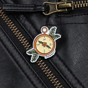 Detail of vintage compass enamel brooch pinned on a black leather jacket texture