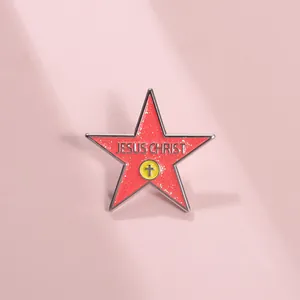 Close-up of a red glitter star-shaped enamel pin with Jesus Christ text and cross