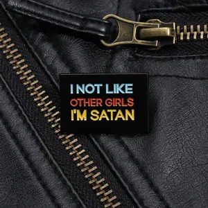 Close-up of Satan-themed enamel pin on black leather jacket showing sharp text details