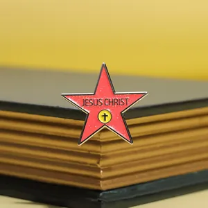 Detailed view of a red star-shaped religious brooch with Jesus Christ text on a book
