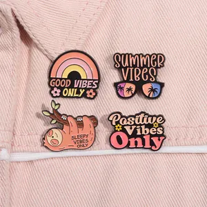 Détail de quatre épingles en émail d'été avec arc-en-ciel et paresseux sur denim rose