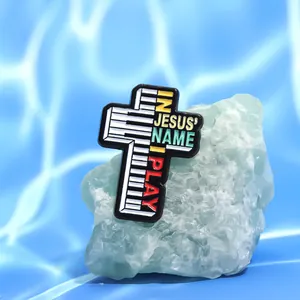 Détail de la broche en émail en forme de croix avec touches de piano et texte